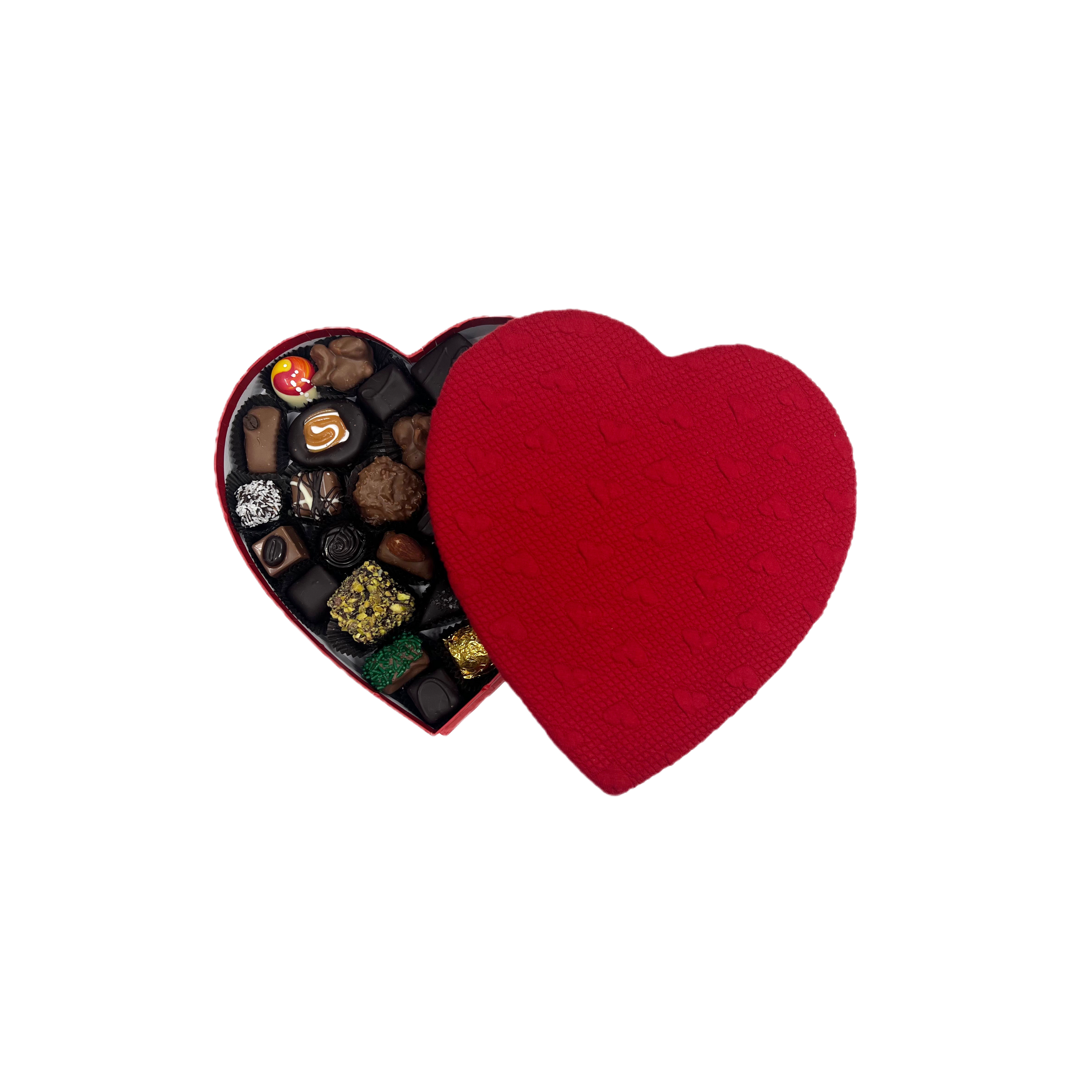 Red heart-shaped box filled with assorted chocolates on a white background