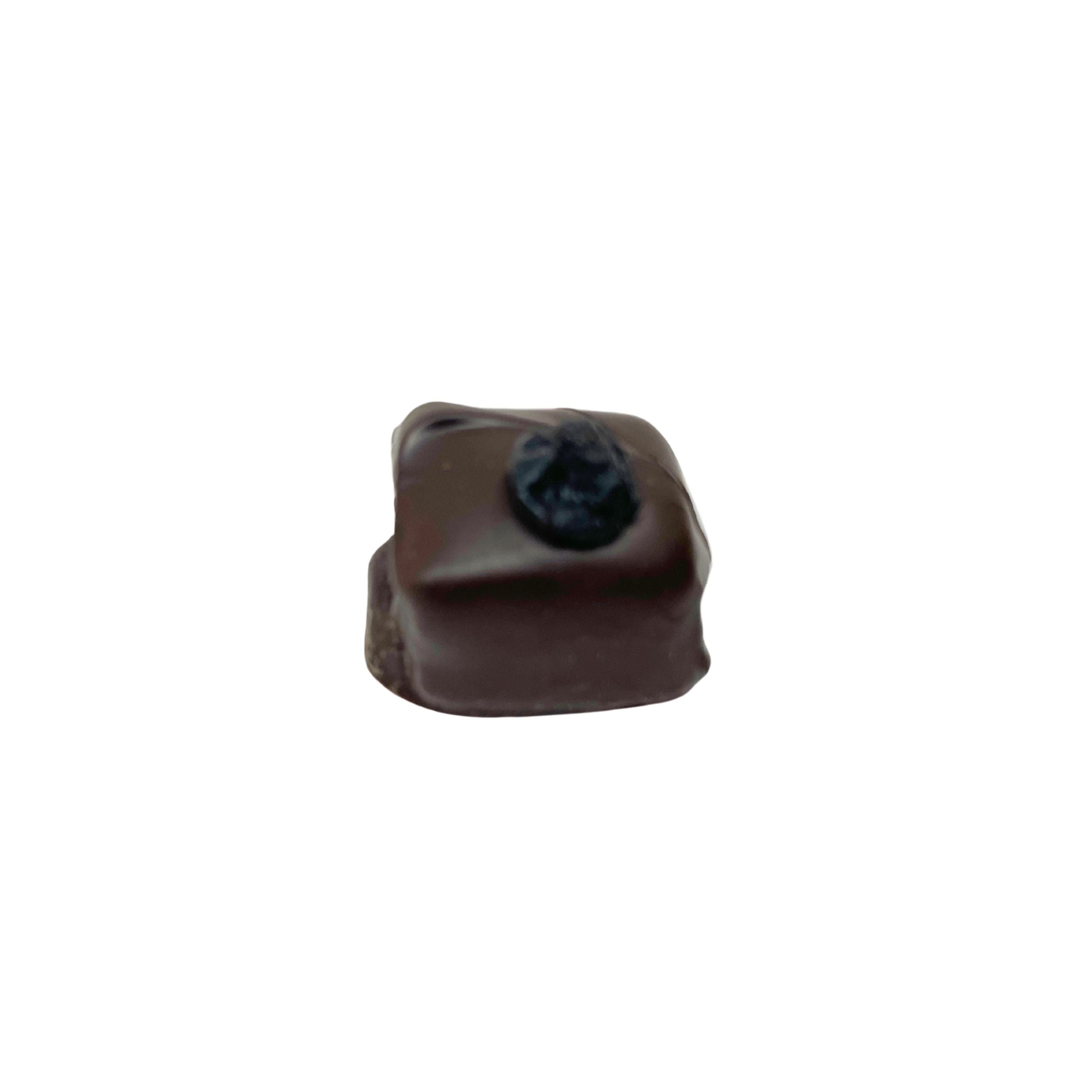 A single square chocolate candy with a dark, textured center, isolated on a solid white background.