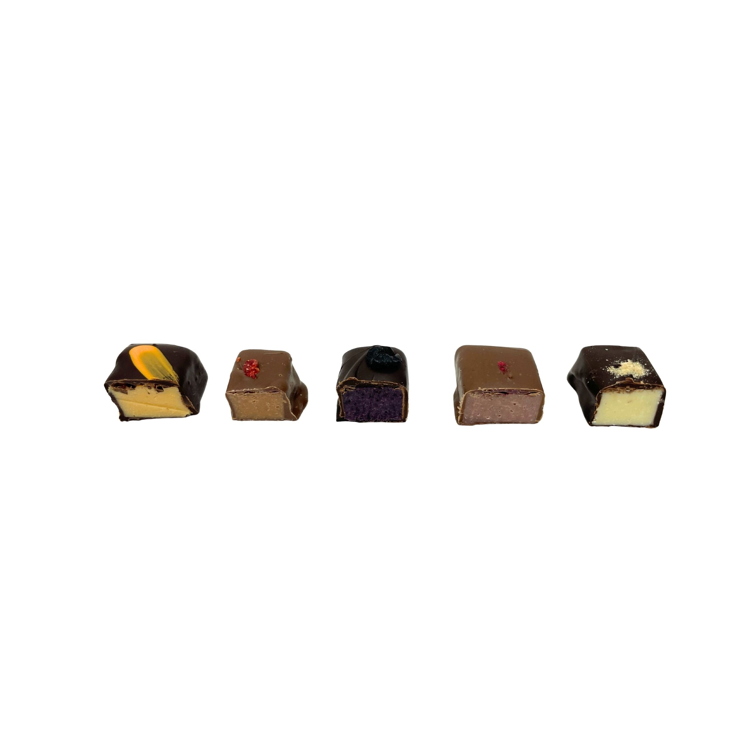 Five small chocolate pieces arranged in a row on a plain white background, including dark chocolate, milk chocolate, and some with cream-colored centers and small red or yellow toppings.