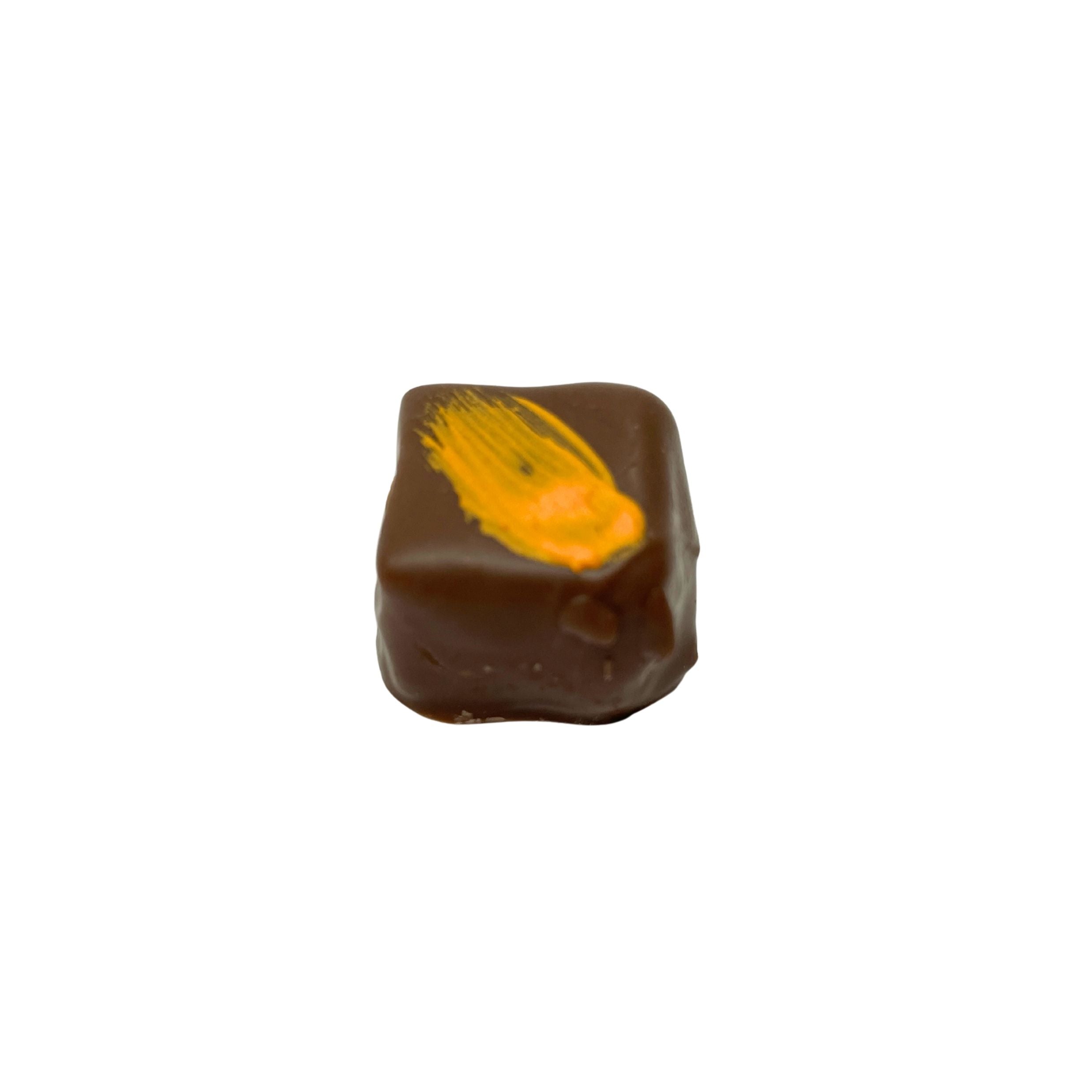 A single square dark chocolate candy with a bright orange-yellow drizzle on top, isolated on a solid white background.