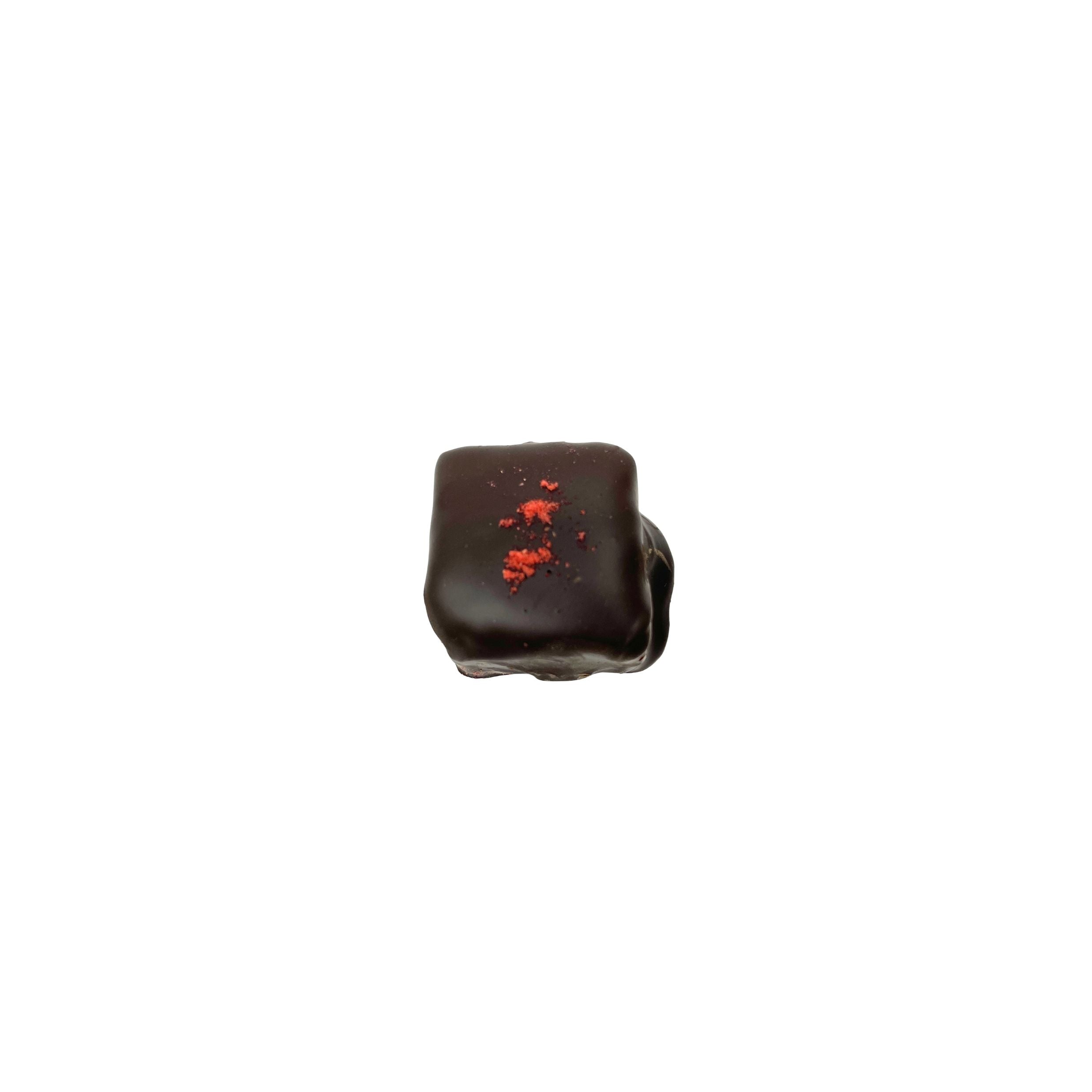 dark chocolate square confection with red speckle on a white background