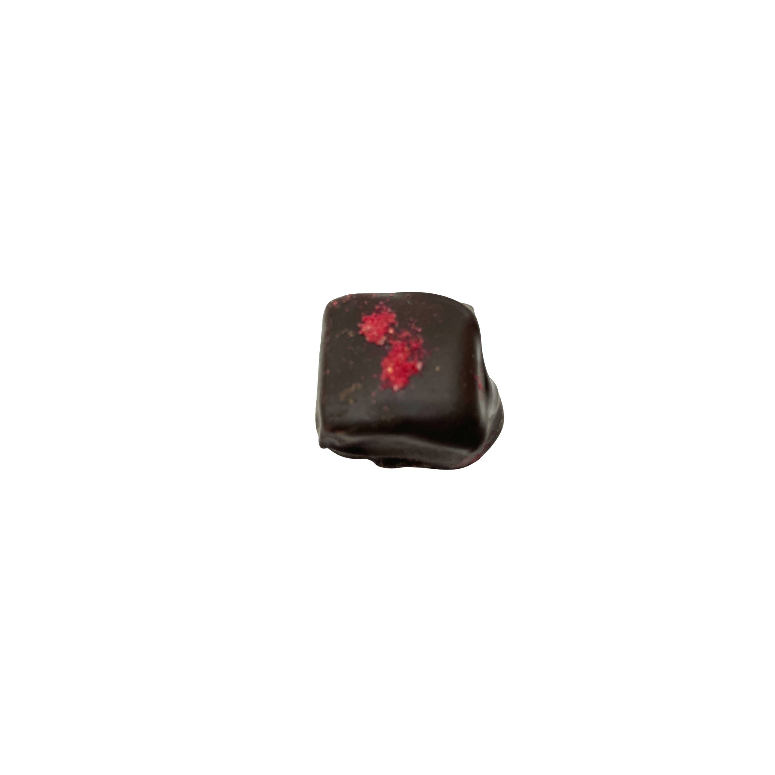 dark chocolate square with red speckle on top on a white background