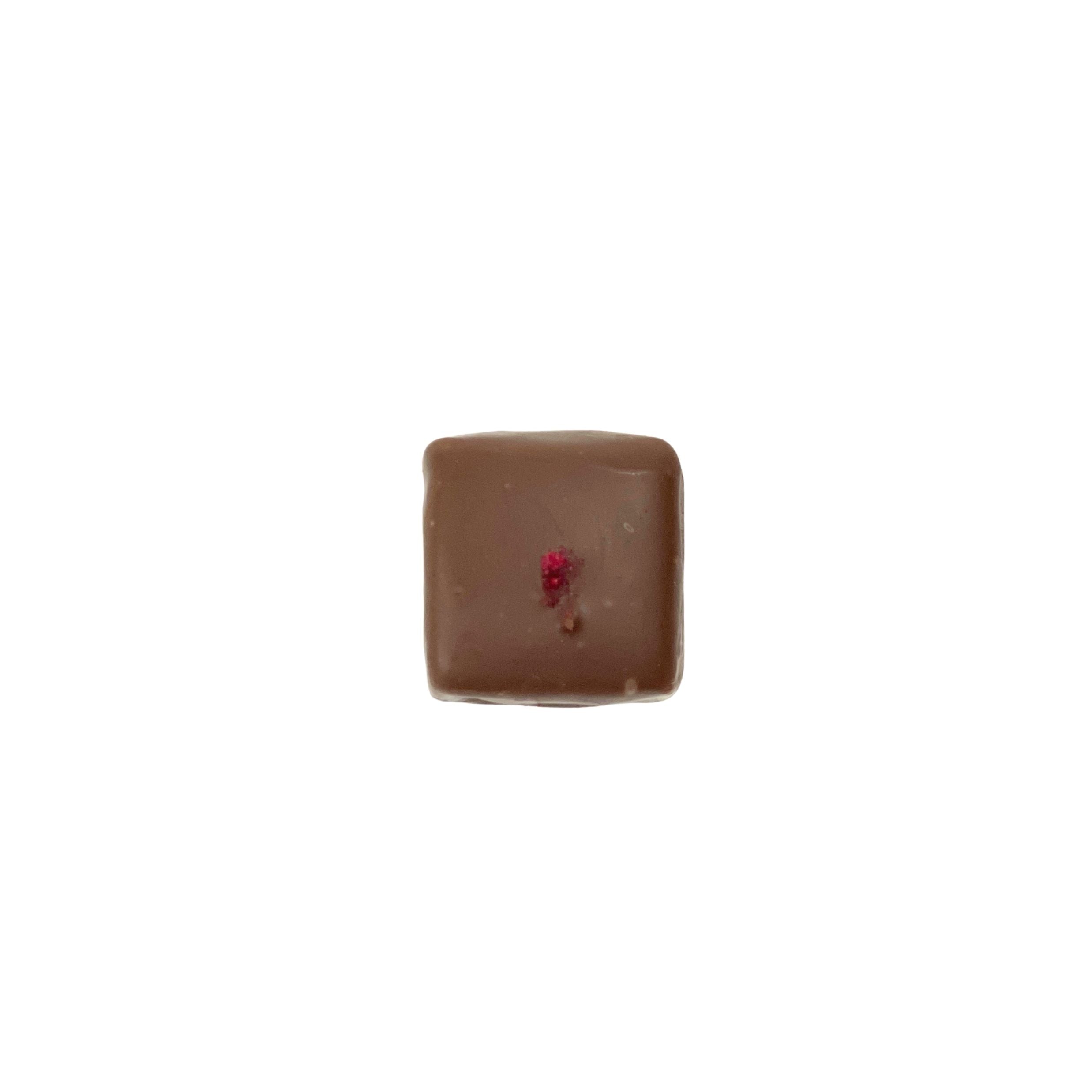 milk chocolate square with red speckles on a white background