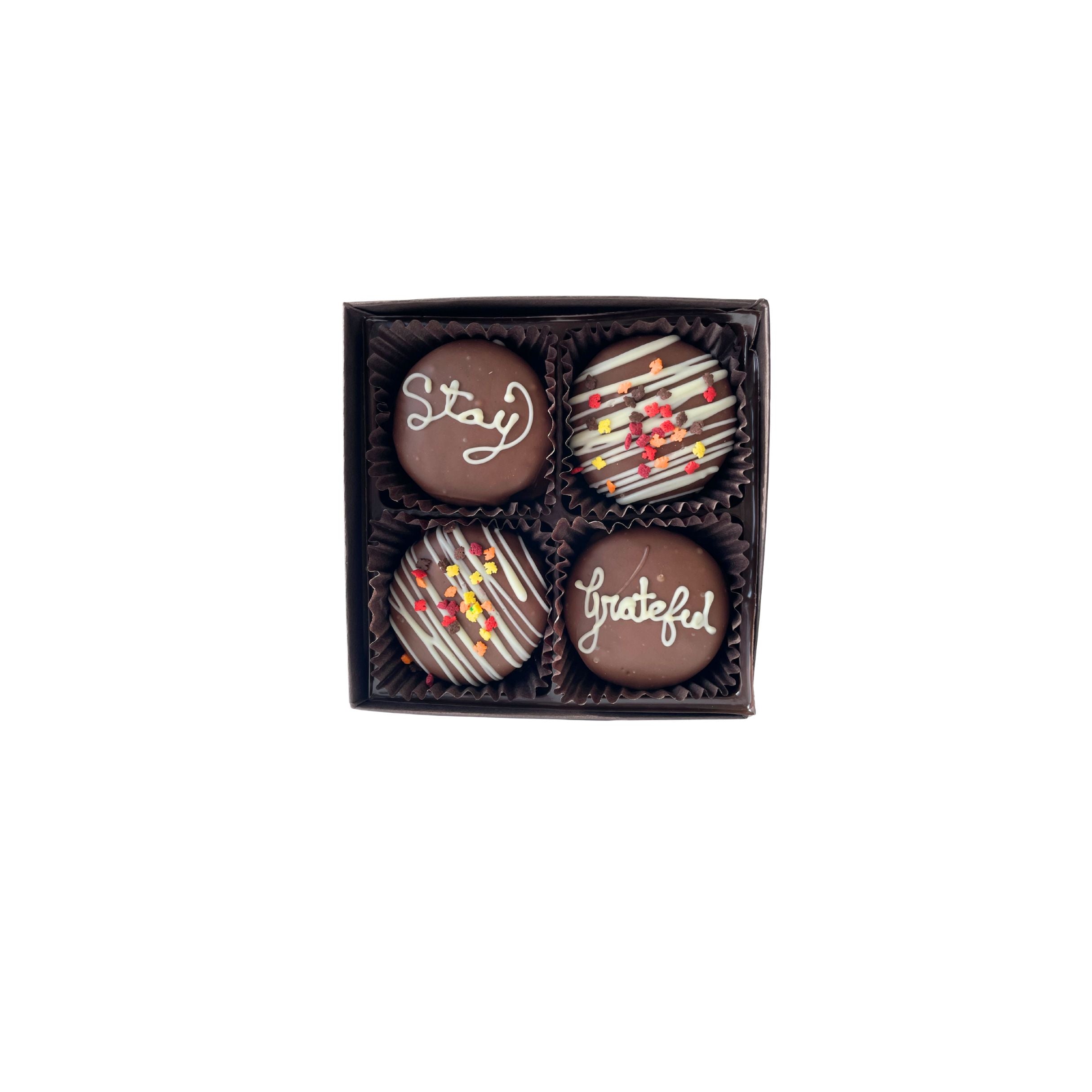 Four chocolate oreos in a box with personalized text on a white background