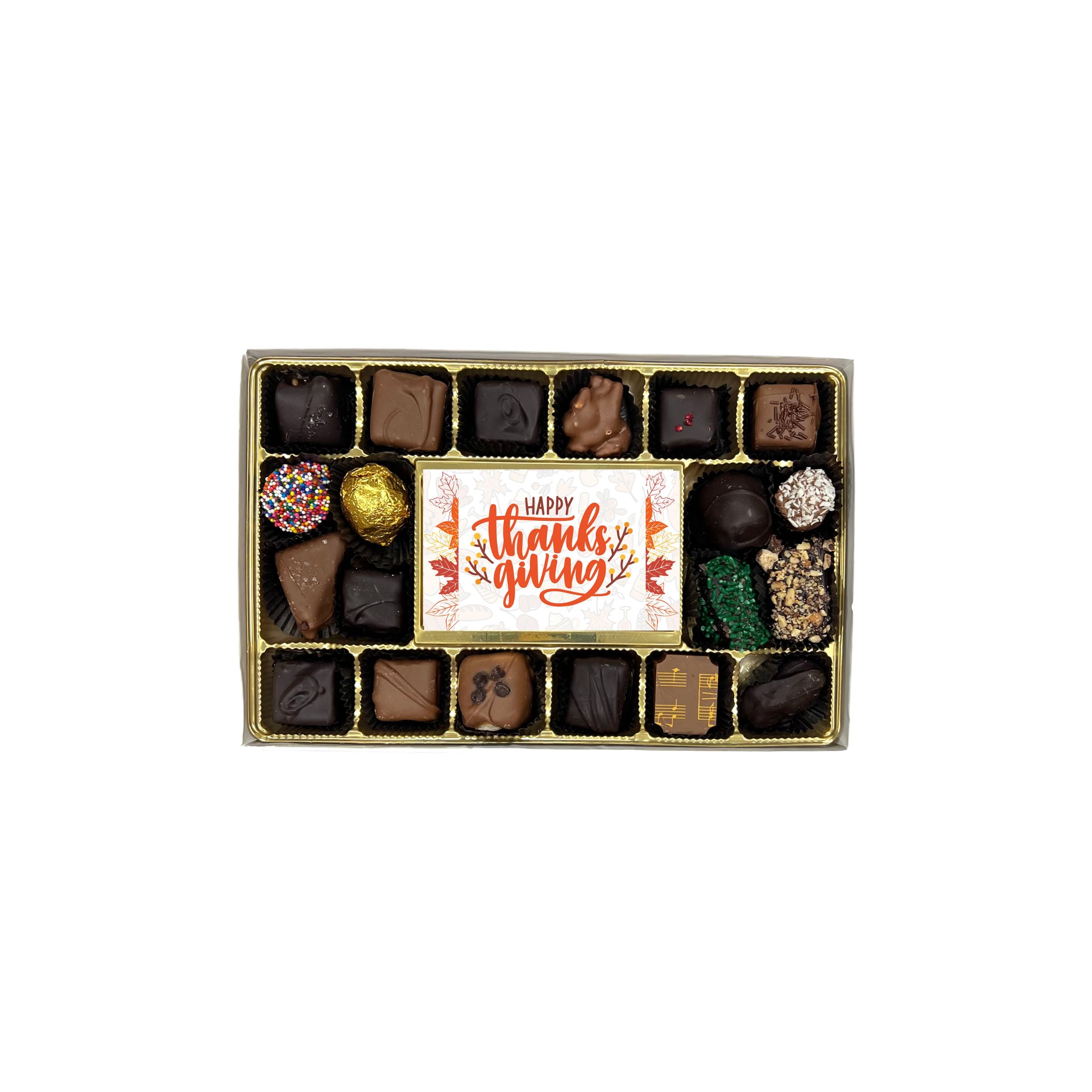 Box of assorted chocolates with a 'Happy Thanksgiving' card on a white background