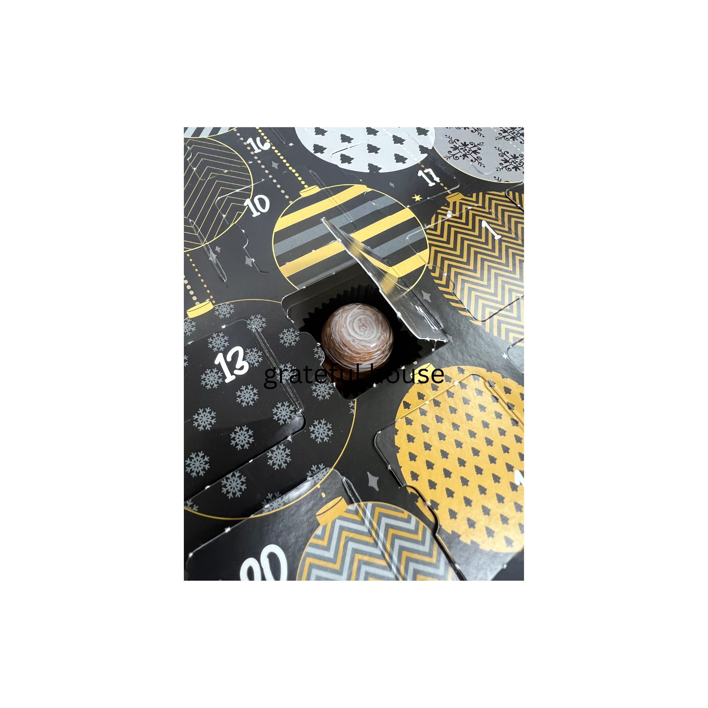 Decorative advent calendar with geometric patterns and a small door open, showing a ball inside.