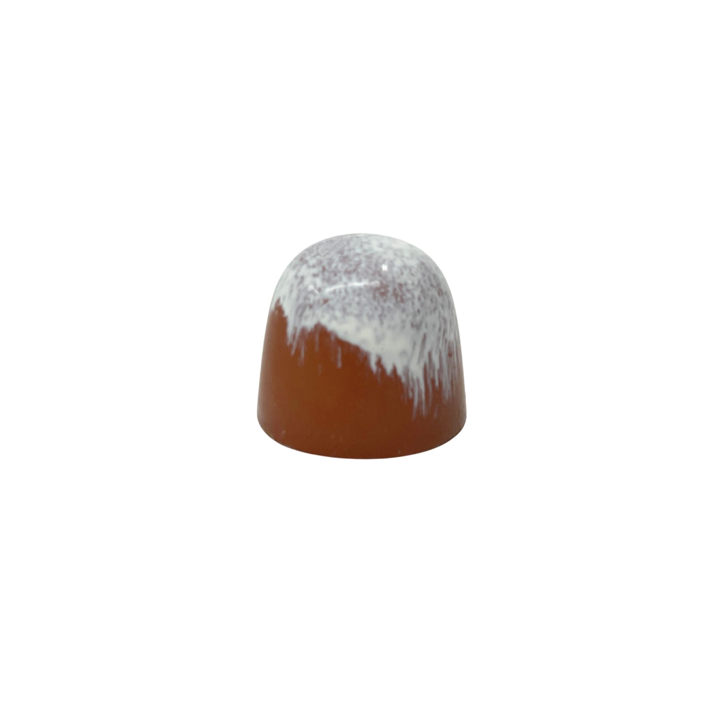 A small dome-shaped chocolate with a glossy reddish-brown lower body and a white glazed top with dripping edges, centered on a plain white background.