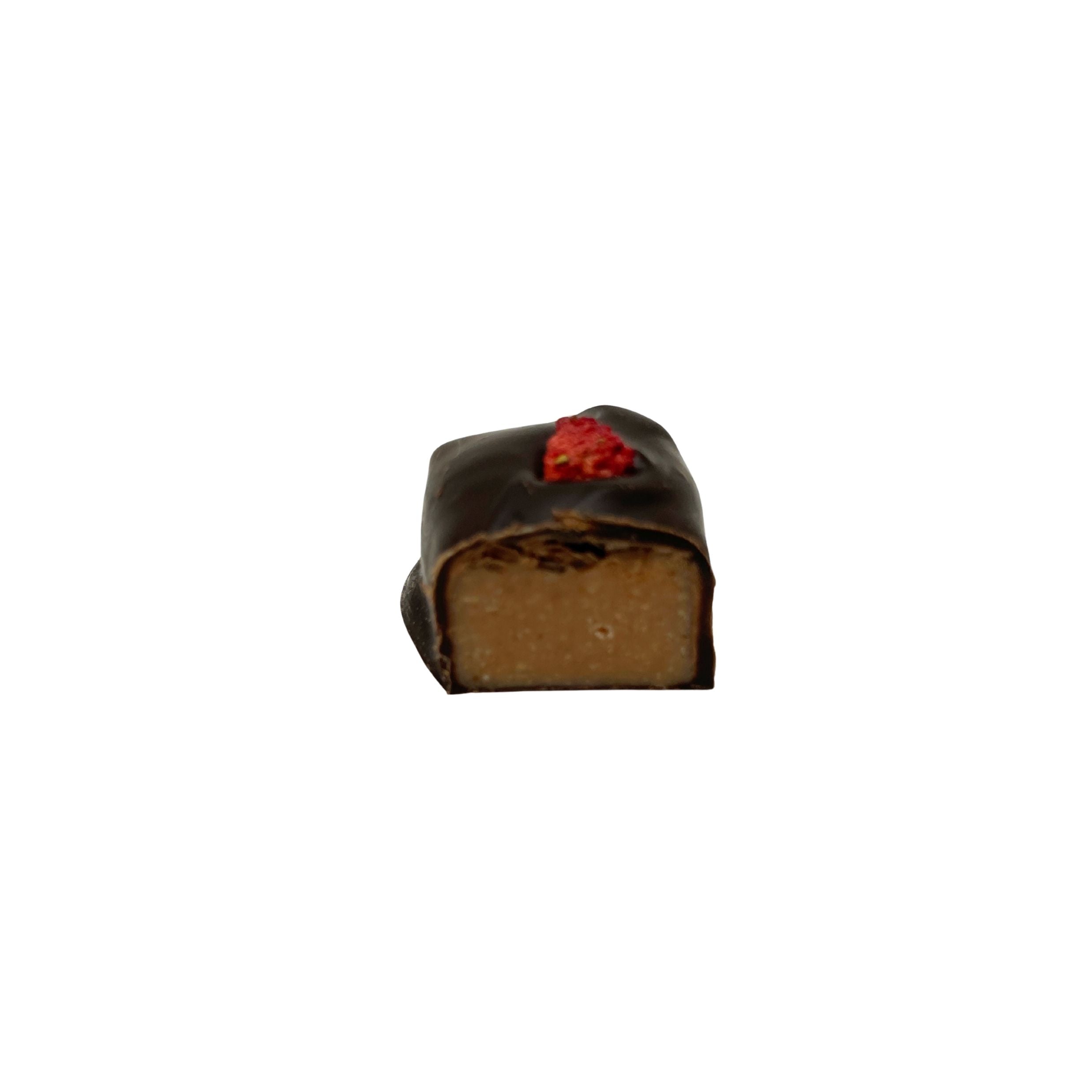 A single square chocolate confection with a dark chocolate coating, a light brown center, and a small red fruit topping, isolated on a white background.